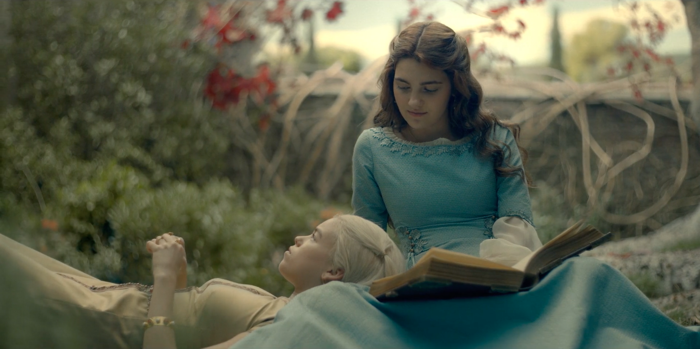 Rhaenyra Targaryen and Alicent Hightower lie on each other's lap as kids